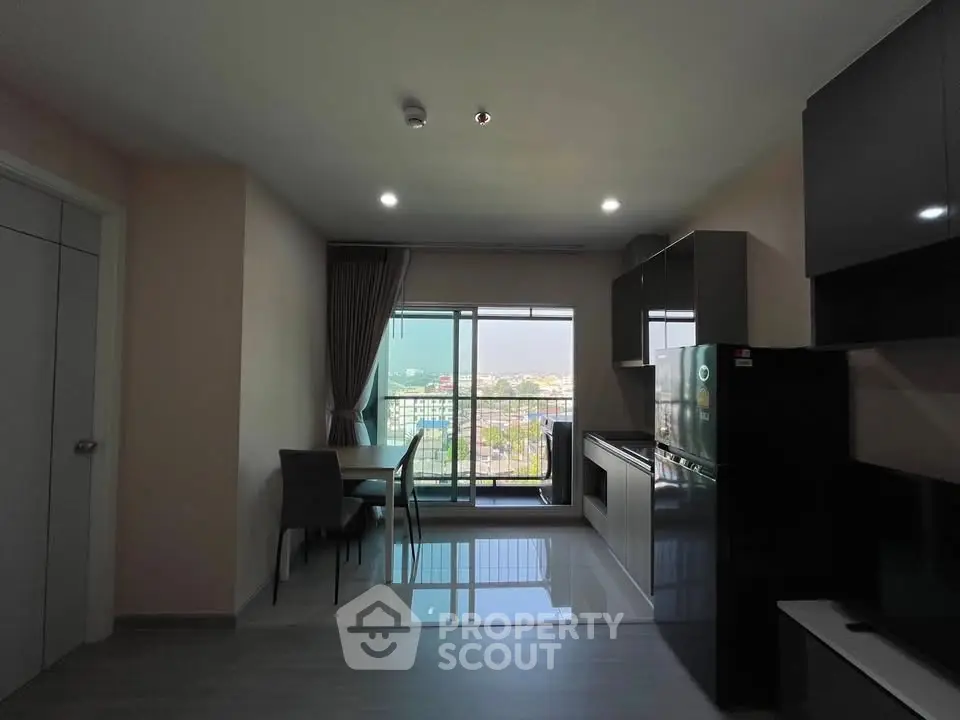 Modern apartment with open kitchen and balcony view, featuring sleek cabinetry and dining area.