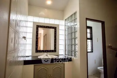 Spacious bathroom with modern sink and glass block wall