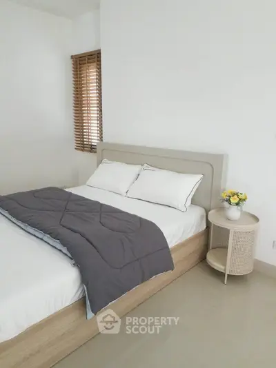 Cozy bedroom with modern decor and natural light, featuring a comfortable bed and stylish side table.