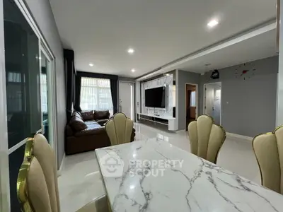 Elegant open-plan living and dining area with modern decor and marble table.