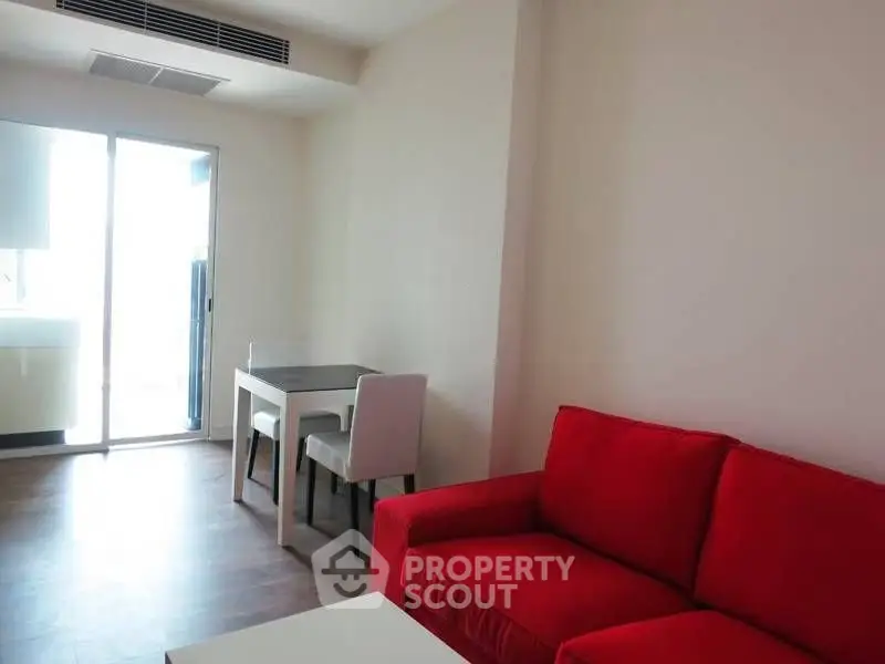 Modern living room with red sofa and dining area in bright apartment