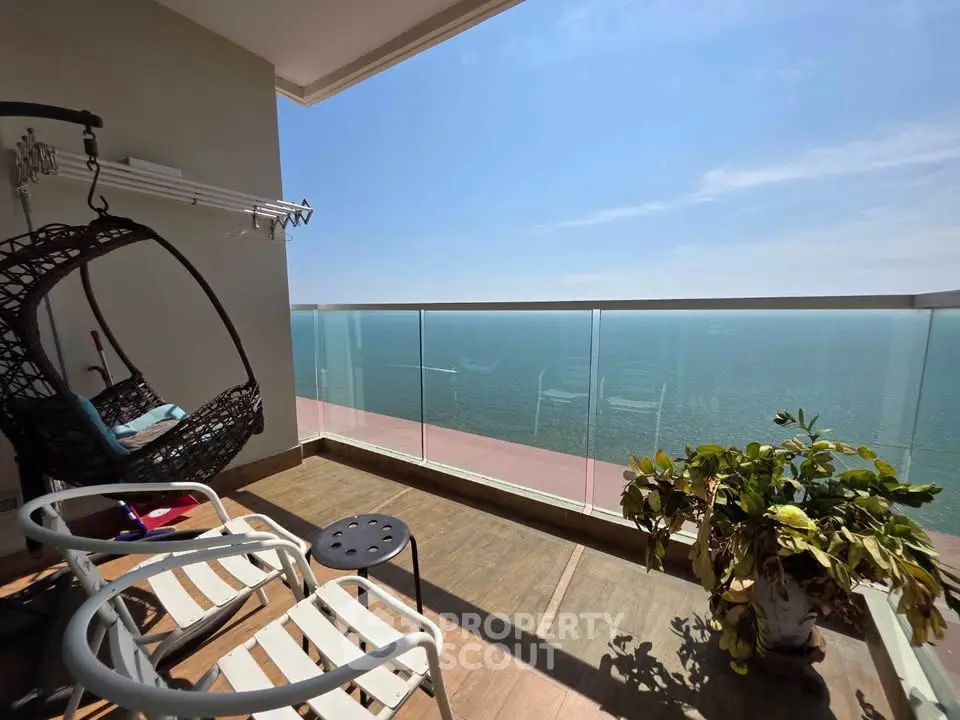 Stunning ocean view from a modern balcony with stylish seating and lush plant.