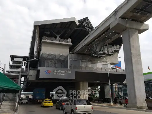 Modern elevated train station with vehicles passing underneath, showcasing urban infrastructure.