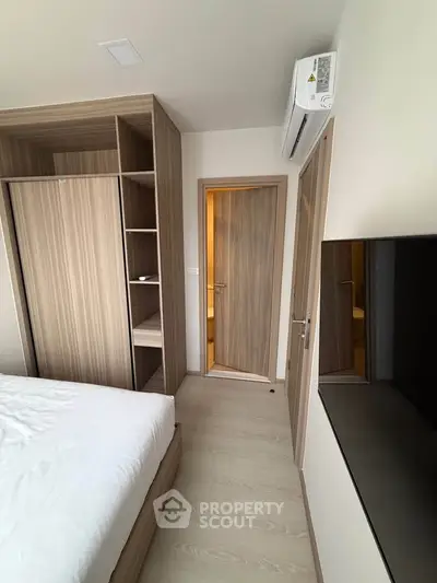 Modern bedroom with wooden wardrobe and air conditioning unit, featuring sleek design and neutral tones.