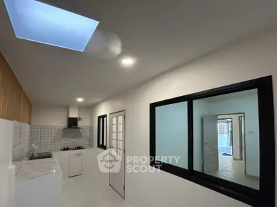 Modern kitchen with sleek design and skylight, featuring a gas stove and ample natural light.