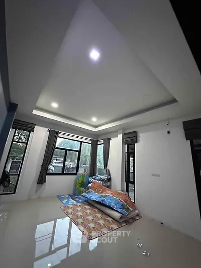 Spacious living room with large windows and modern ceiling design, perfect for natural light.