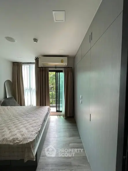 Modern bedroom with balcony access and natural light, featuring sleek design and air conditioning.