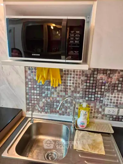 Modern kitchen with microwave, stainless steel sink, and stylish mosaic backsplash