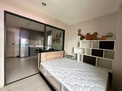 Modern bedroom with open layout to kitchen, featuring stylish shelving and sleek design.