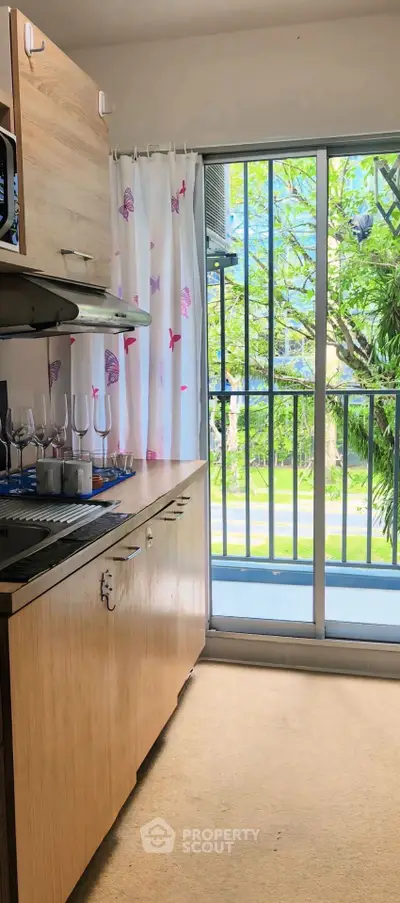 Charming kitchen with open layout and balcony view, featuring modern cabinetry and elegant glassware display.
