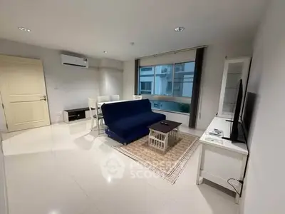 Modern living room with sleek furniture and large window offering natural light.