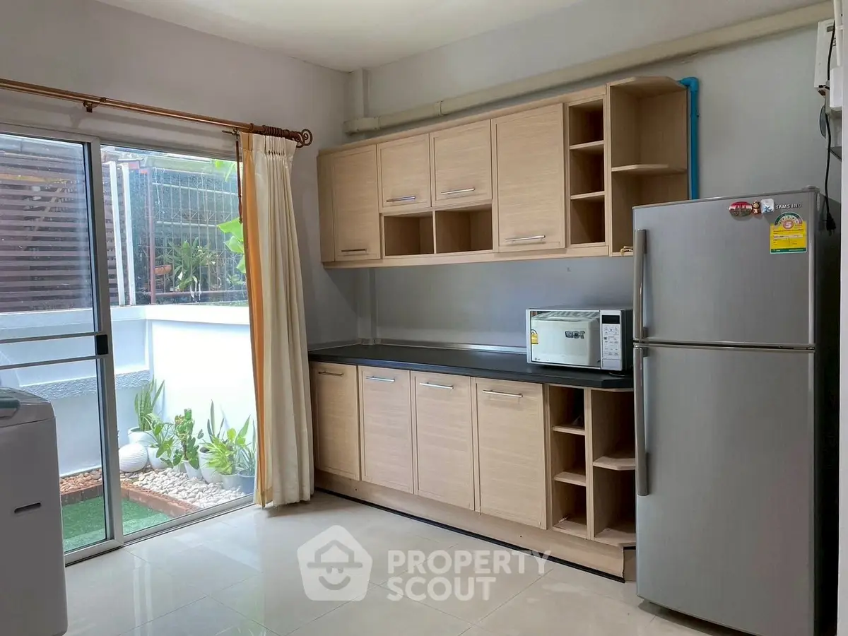 Modern kitchen with sleek cabinetry and stainless steel appliances, featuring a large window for natural light.