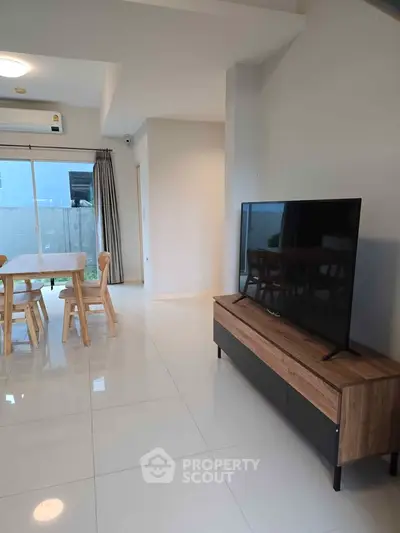 Modern living room with sleek TV stand and dining area, bright and spacious.