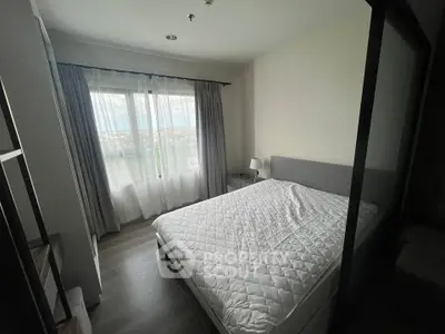 Cozy bedroom with large window and modern furnishings in a stylish apartment.