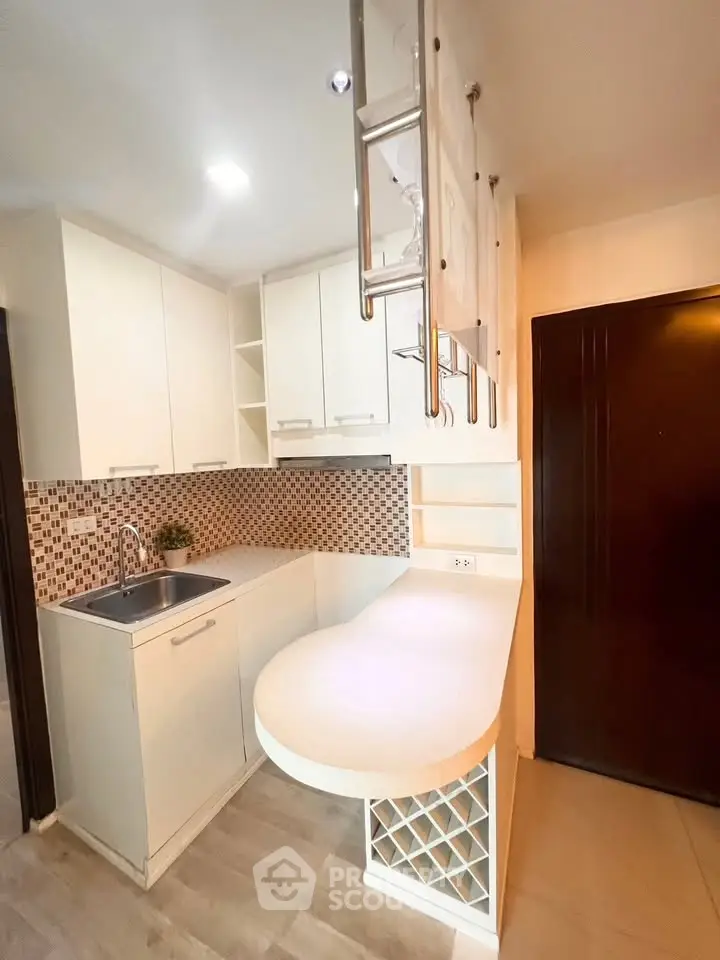 Modern kitchen with sleek white cabinets and unique hanging storage, perfect for compact living spaces.