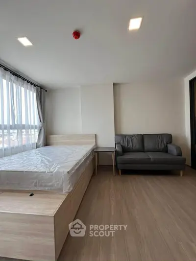 Modern bedroom with natural light, featuring a bed and cozy sofa, ideal for relaxation.
