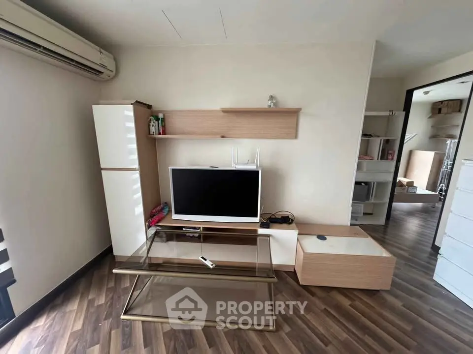 Modern living room with sleek furniture and wooden flooring, featuring a TV and stylish shelving.