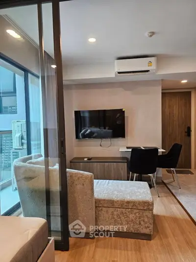 Modern living room with balcony, featuring sleek furniture and a wall-mounted TV.