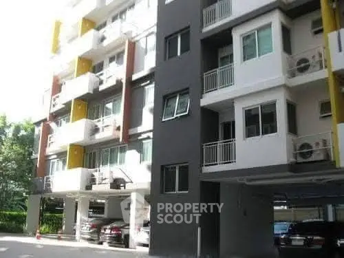 Modern apartment building exterior with parking area and balconies.