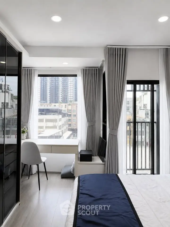 Modern bedroom with city view, large windows, and stylish decor in urban apartment.