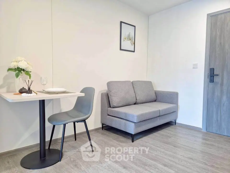 Modern minimalist living room with gray sofa and dining area in cozy apartment.