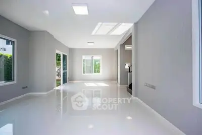 Spacious modern living room with large windows and glossy white flooring