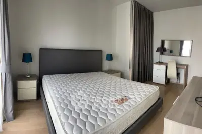 Spacious bedroom with modern decor and natural light, featuring a comfortable bed and stylish furniture.