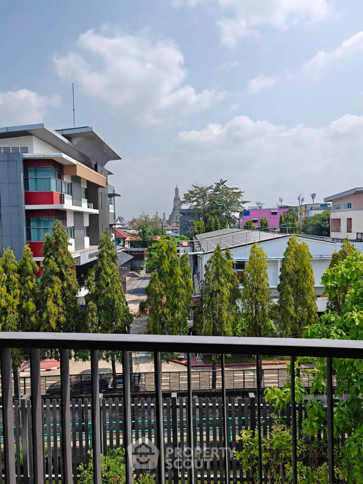Stunning cityscape view from a modern balcony with lush greenery and clear skies.