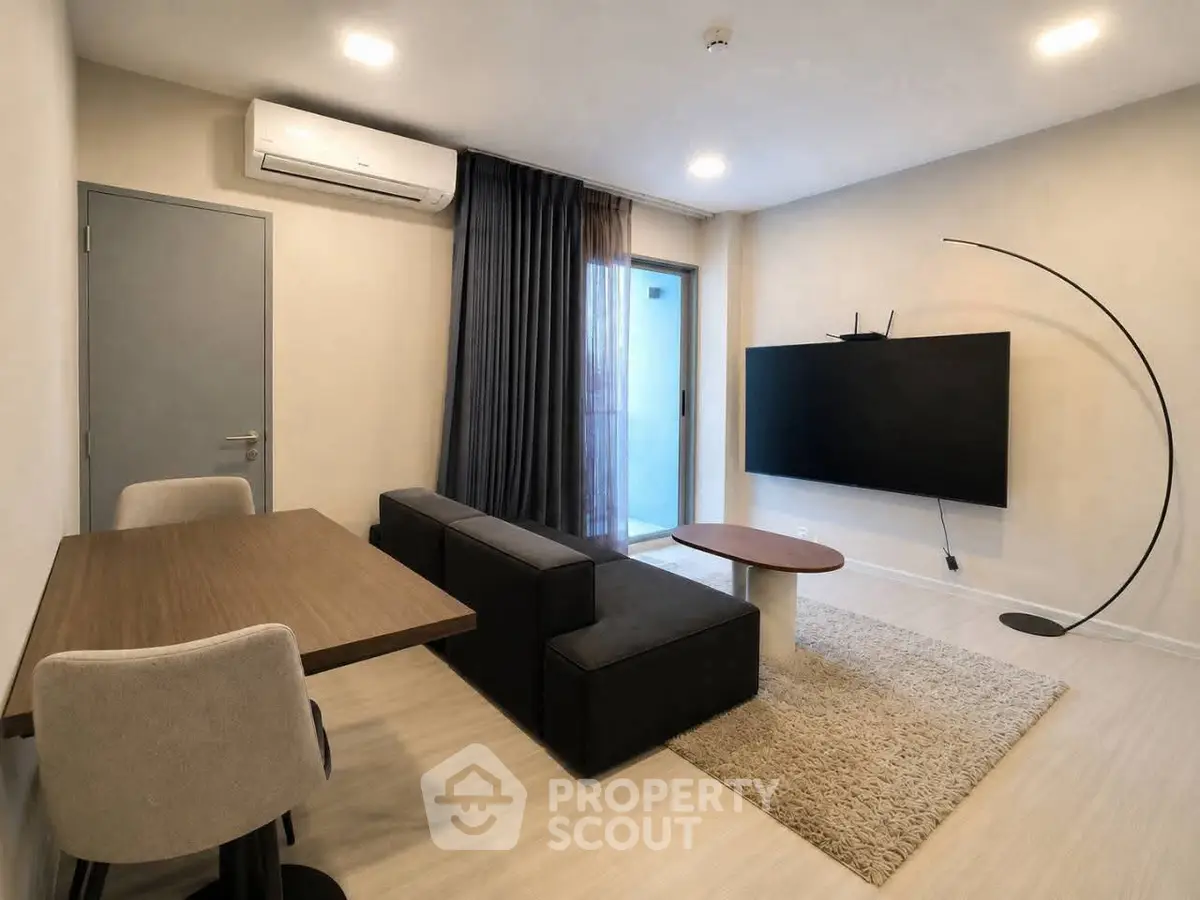 Modern living room with sleek furniture and large TV, featuring a minimalist design and cozy ambiance.