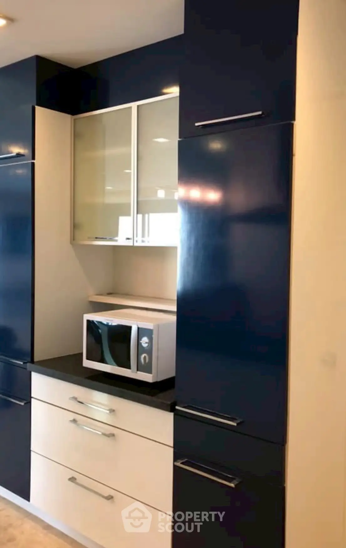 Modern kitchen with sleek blue cabinets and built-in microwave