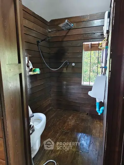 Rustic wooden bathroom with modern shower and toilet, offering a cozy cabin feel.