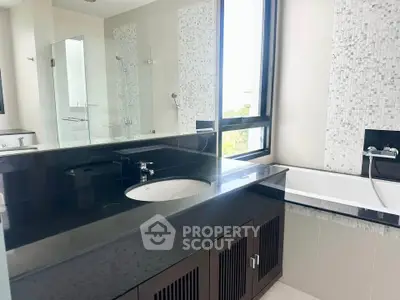 Modern bathroom with sleek black countertop and bathtub in a stylish apartment.