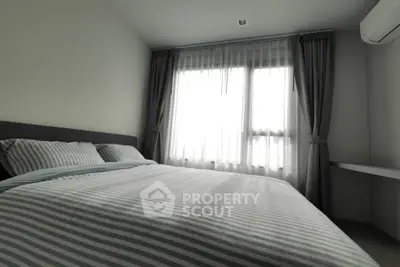 Cozy bedroom with striped bedding and large window with curtains