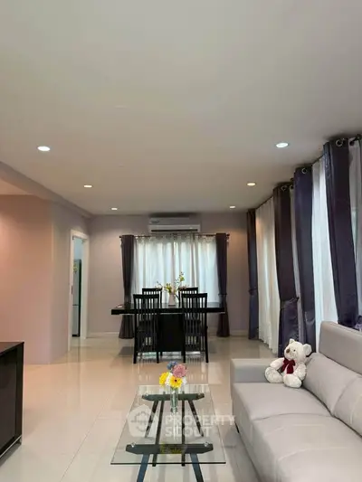 Spacious living room with modern decor and dining area, featuring elegant curtains and cozy seating.