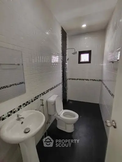Modern bathroom with sleek black and white tiles, featuring a shower and contemporary fixtures.