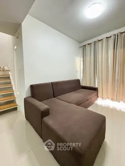 Spacious living room with modern brown sofa and natural light