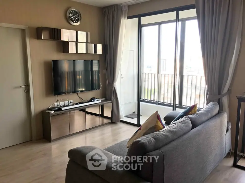 Modern living room with sleek furniture and large windows offering natural light and city views.