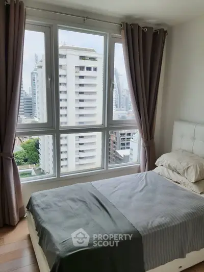 Modern bedroom with large windows offering stunning city views in a high-rise apartment.