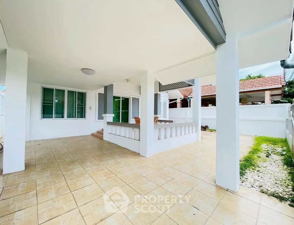 Spacious covered patio with tiled flooring and modern design in a suburban home.