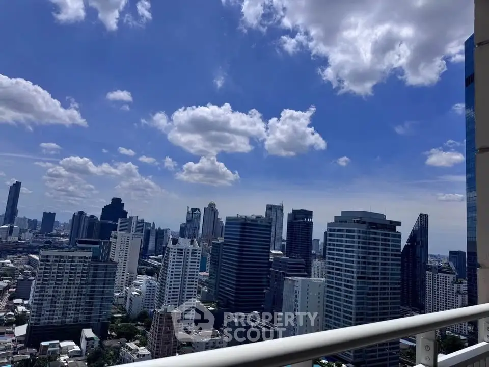 Stunning cityscape view from high-rise balcony with clear blue sky.