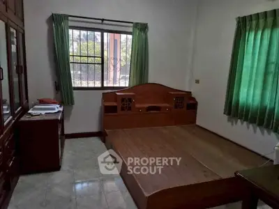 Cozy bedroom with wooden bed frame and green curtains in a well-lit space.