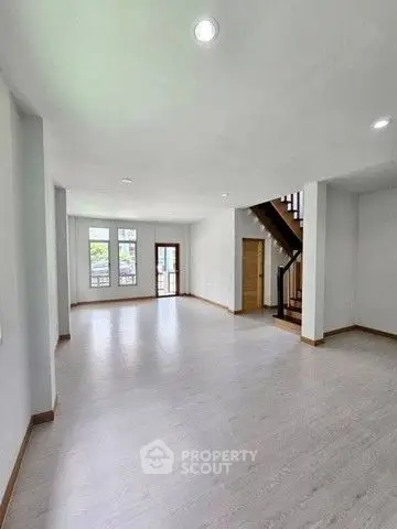 Spacious open-plan living room with modern staircase and large windows