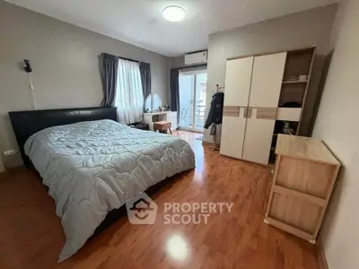 Spacious bedroom with wooden flooring and balcony access in modern apartment.