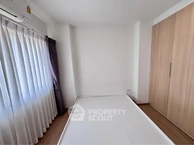 Spacious bedroom with large window and built-in wardrobe, perfect for modern living.