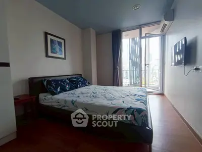 Modern bedroom with balcony view and stylish decor in urban apartment.