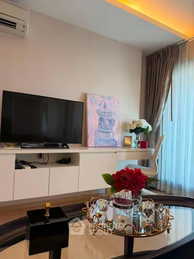 Stylish living room with modern decor, featuring a flat-screen TV, elegant furniture, and a large window with curtains.
