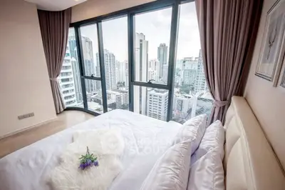 Luxurious bedroom with stunning city view and floor-to-ceiling windows in modern high-rise apartment.