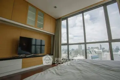 Luxurious bedroom with stunning city view and modern entertainment setup.
