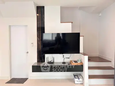 Modern living room with sleek TV setup and stylish staircase design