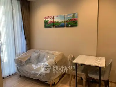 Cozy living room with modern decor and natural light, featuring a small dining table and comfortable seating.